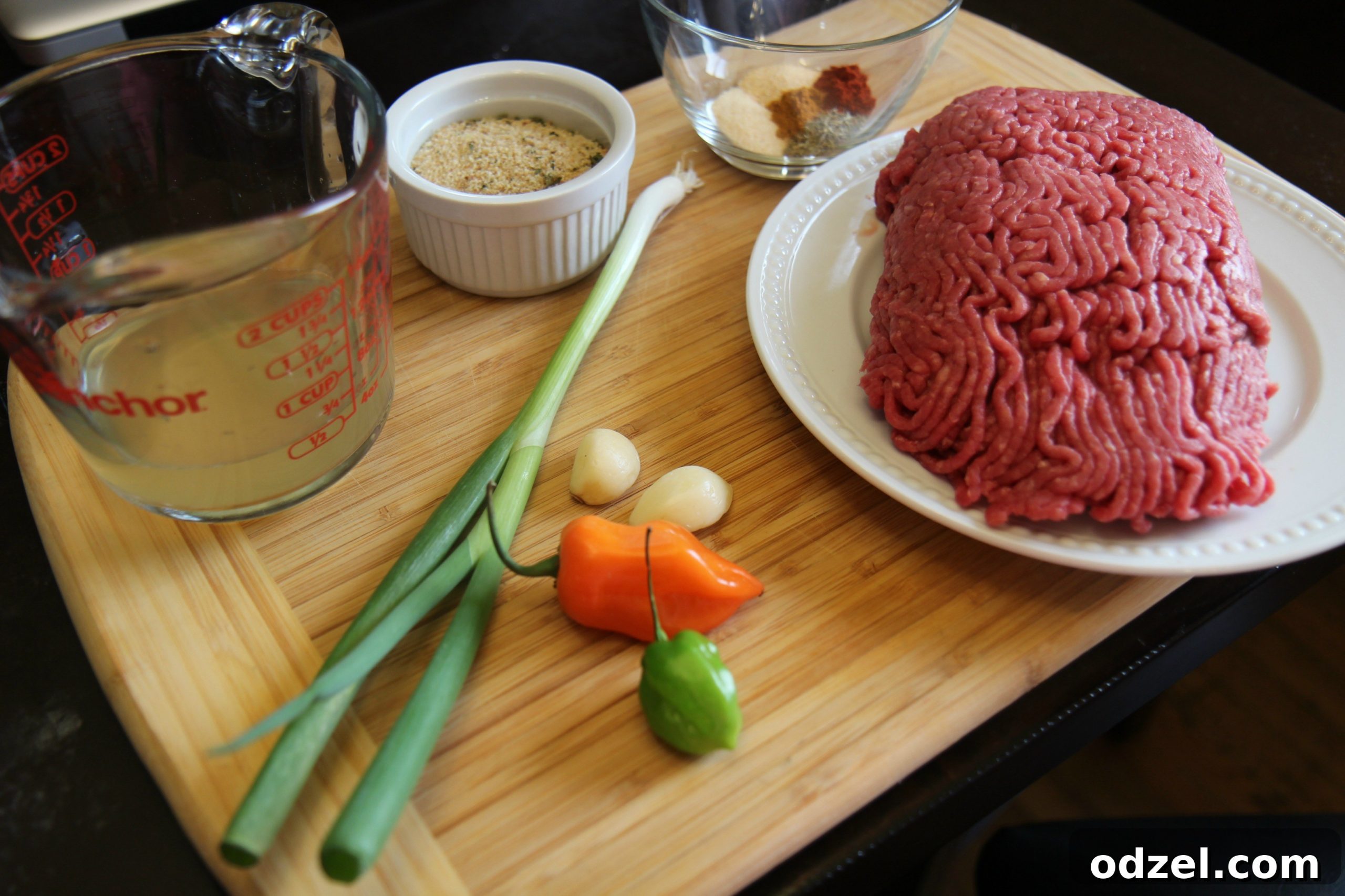 A vibrant selection of ingredients for the beef filling, including ground beef, green onions, and peppers, arranged on a cutting board.
