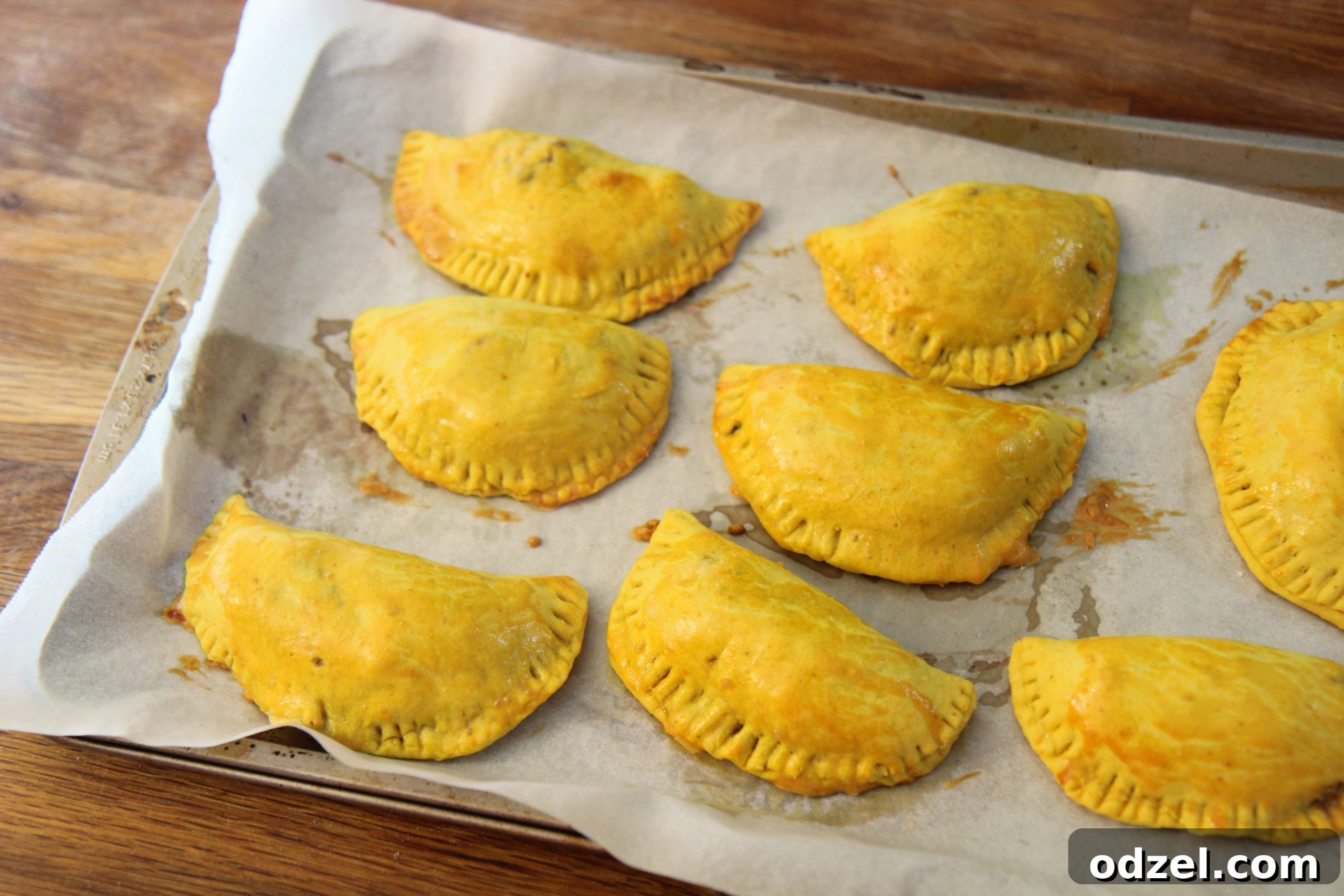 Freshly baked Jamaican Beef Patties, golden brown and flaky, cooling on a rack after coming out of the oven.