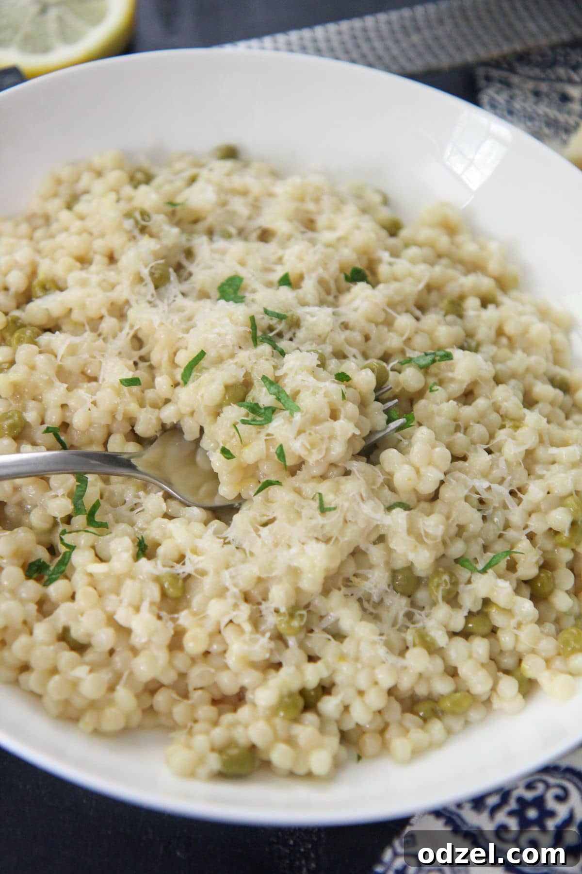 lemon pearl couscous in a white plate with a fork 