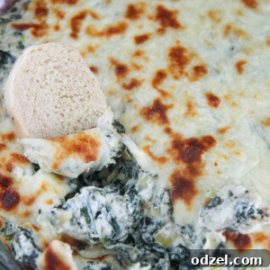 spinach and artichoke dip in a glass bowl with bread