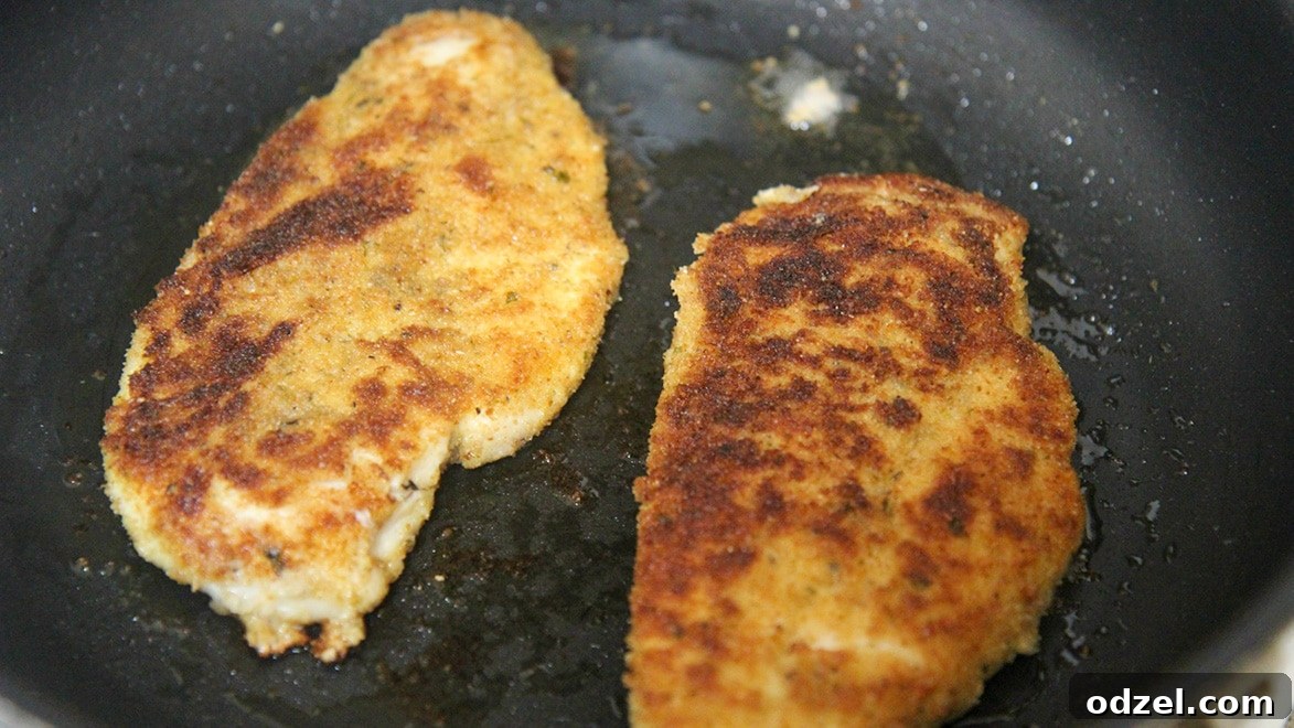 Tuscan Chicken Bruschetta 4 Two perfectly pan-fried golden-brown chicken breasts resting in a black cast-iron skillet, ready for the bruschetta topping and balsamic glaze.