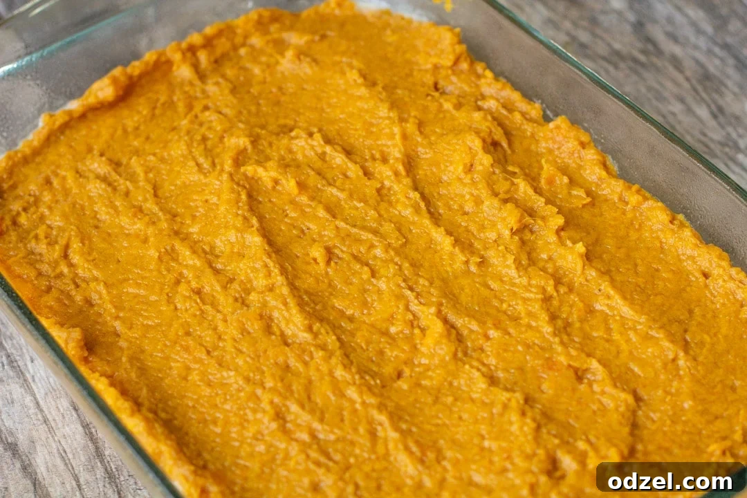 Golden Sweet Potato Bliss 6 Layered mashed sweet potatoes evenly spread in a clear glass baking dish