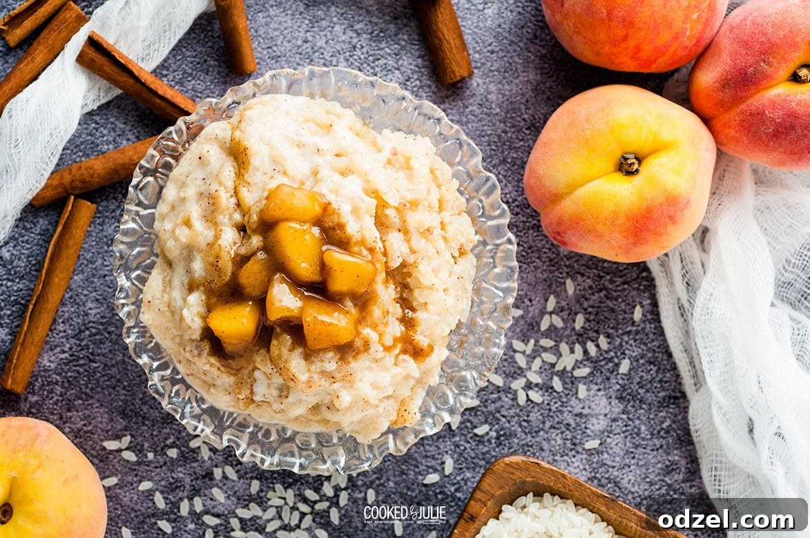 Sun-Kissed Peach Rice Pudding 5 A serving of creamy rice pudding in a clear glass bowl, adorned with cinnamon sticks and fresh peach slices on the side