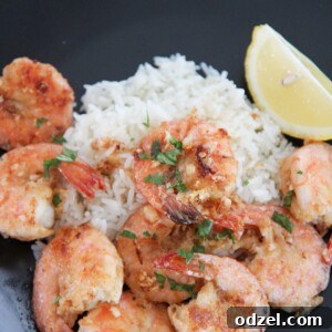 Hawaiian garlic shrimp, white rice, and lemon on a black plate