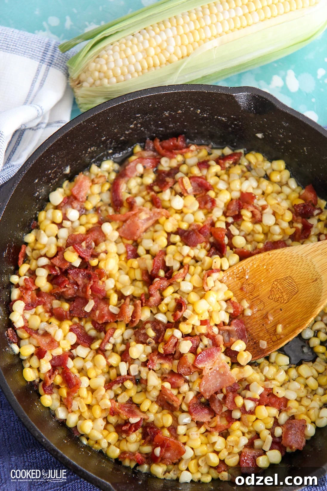 Bacon-Kissed Southern Fried Corn 2 Close-up of golden Southern fried corn with crispy bacon pieces in a black cast iron skillet, served with a wooden spoon.
