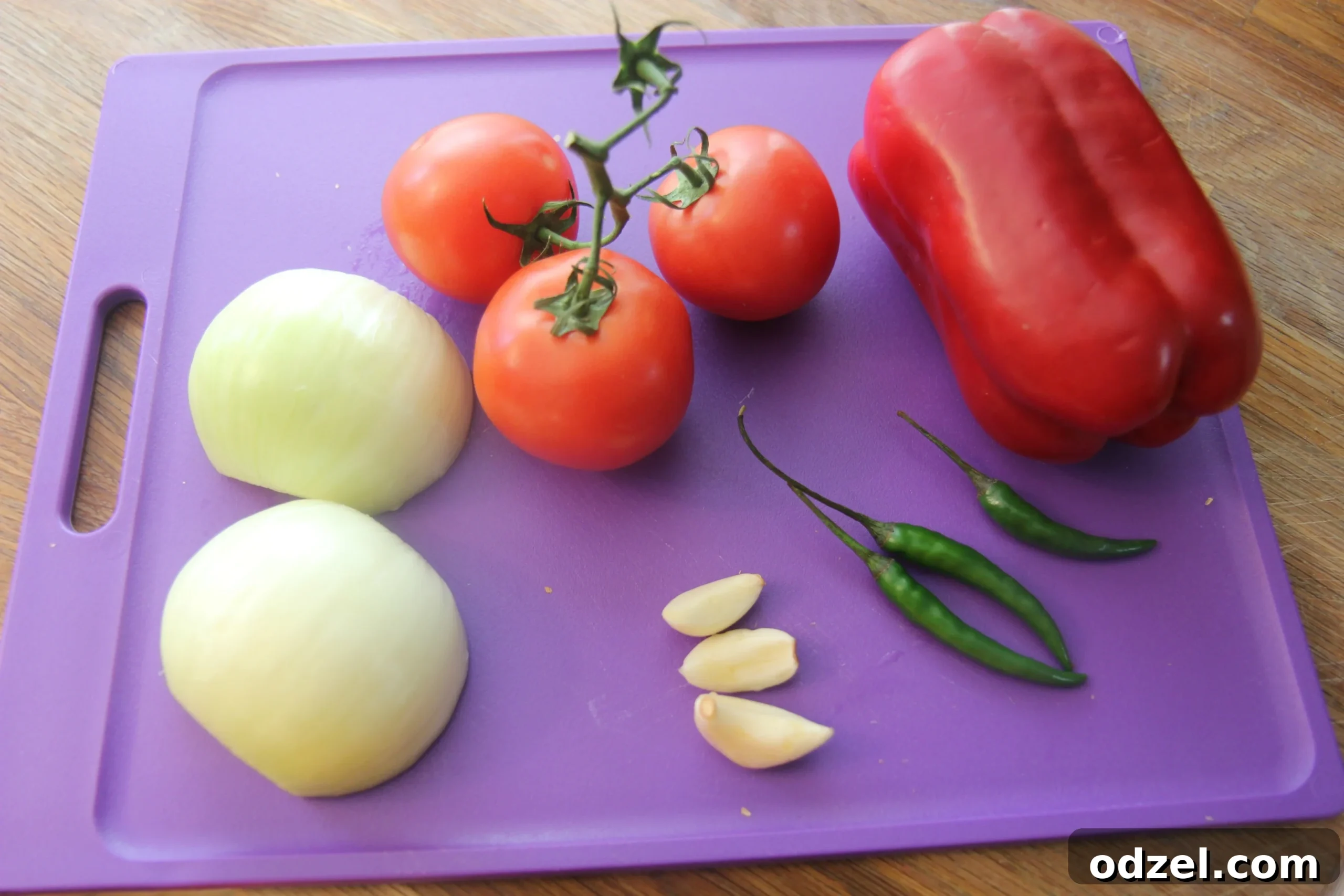 Fresh ingredients for spicy chicken tortilla soup laid out on a purple cutting board, including chicken, tomatoes, onions, and spices.