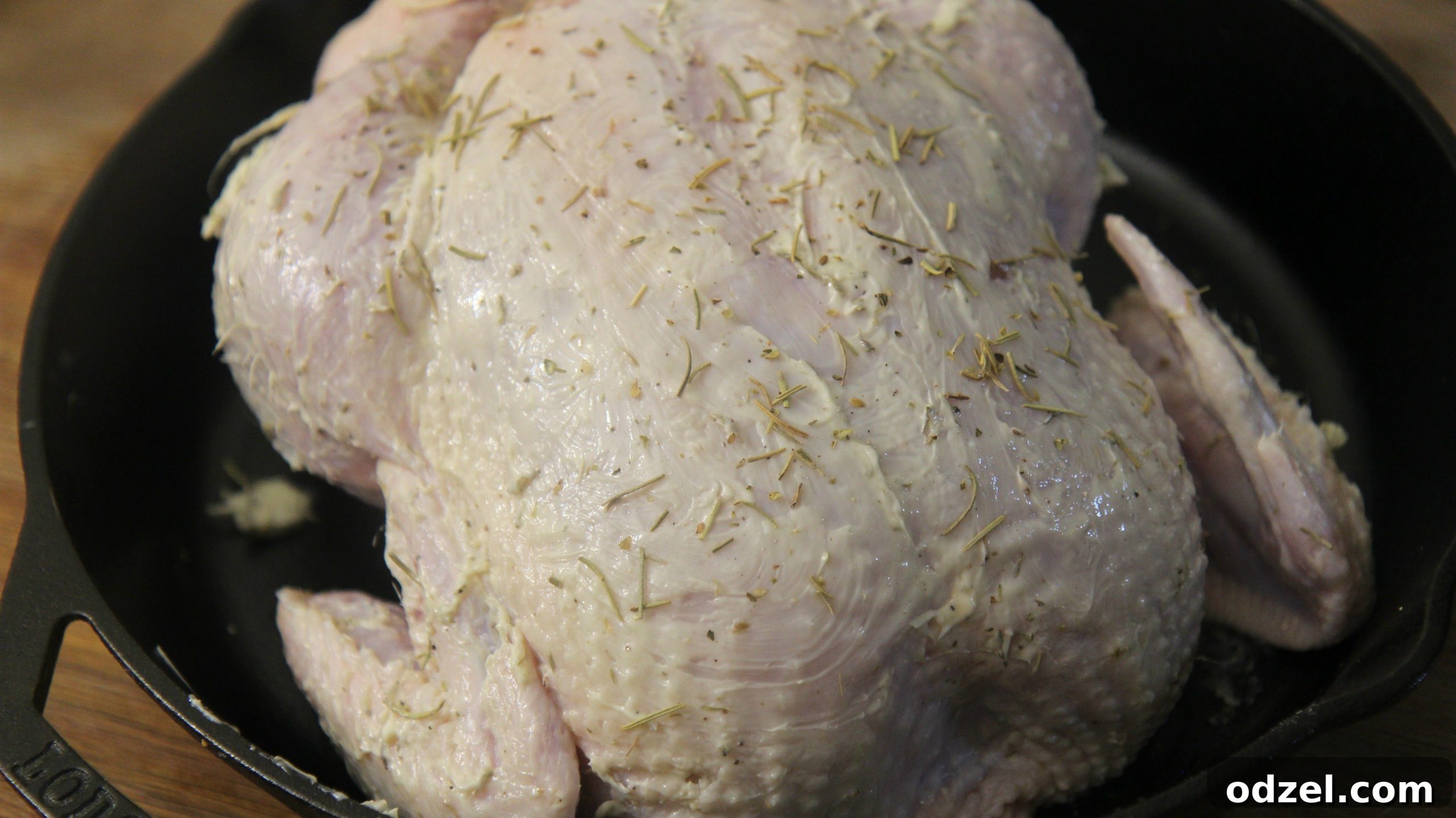 Close-up of a whole chicken being generously rubbed with a homemade herb butter mixture under the skin and over the exterior, ready for roasting to create crispy, flavorful skin.