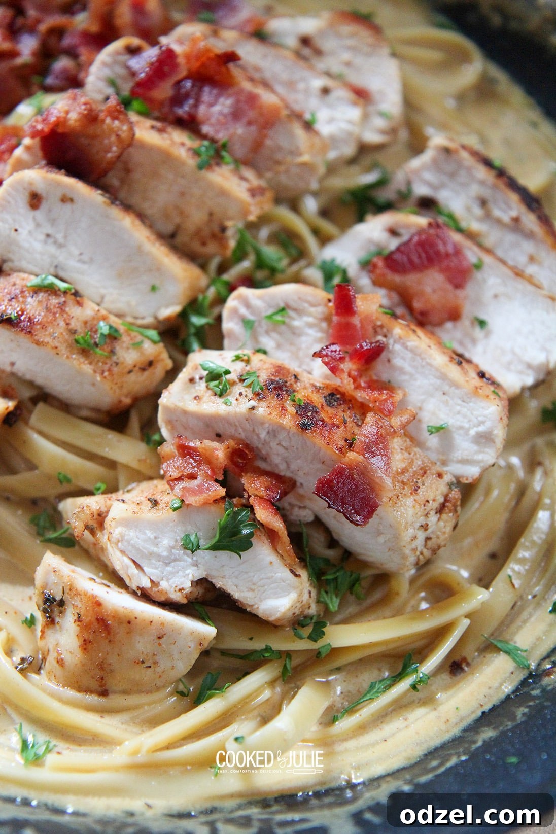 Creamy chicken, bacon, and fettuccine pasta served in a black skillet, ready to eat.