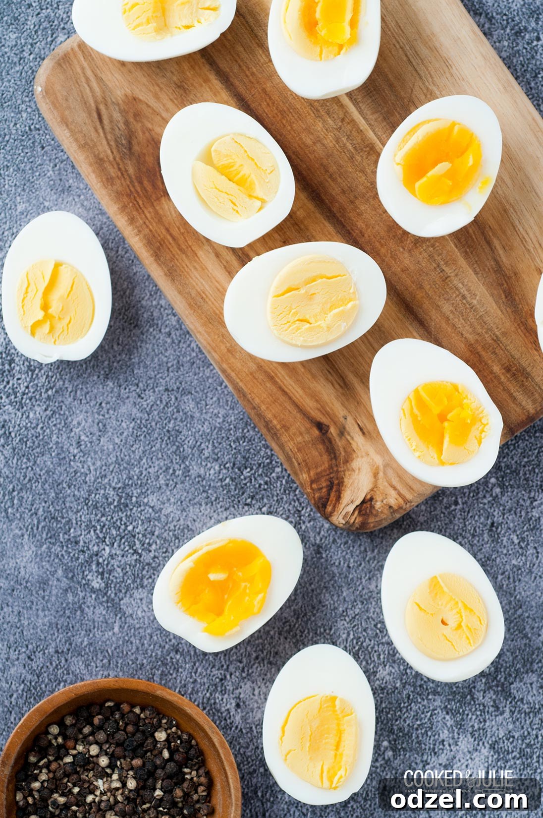 Two halves of a perfectly boiled egg, one showing a runny yolk, the other a firm yolk, served with a pinch bowl of salt and pepper
