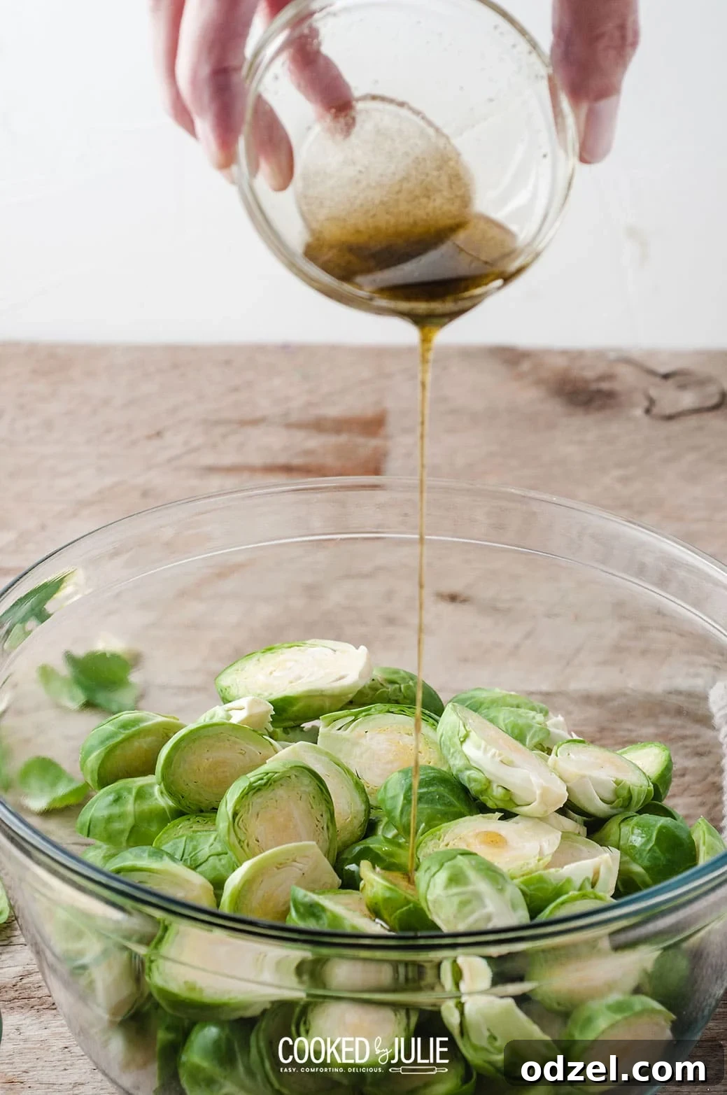 a small bowl with olive oil drizzling over vegetables