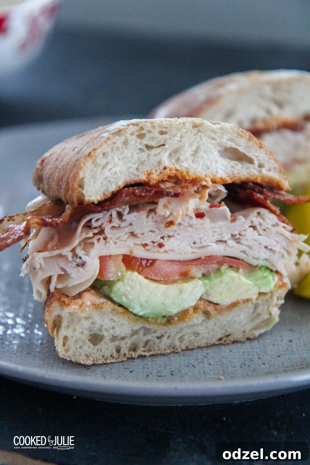 Loaded Turkey Bacon Avocado Dream 2 Delicious turkey bacon avocado sandwich perfectly sliced on a modern gray plate, ready to eat.