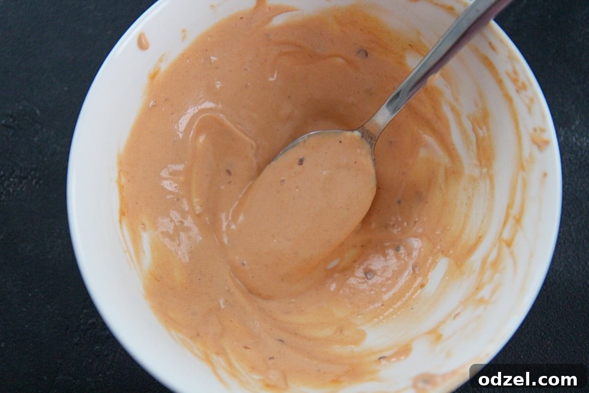 Loaded Turkey Bacon Avocado Dream 4 A bowl of freshly made chipotle mayo with a spoon, showcasing its smooth texture, ready to be used or stored.