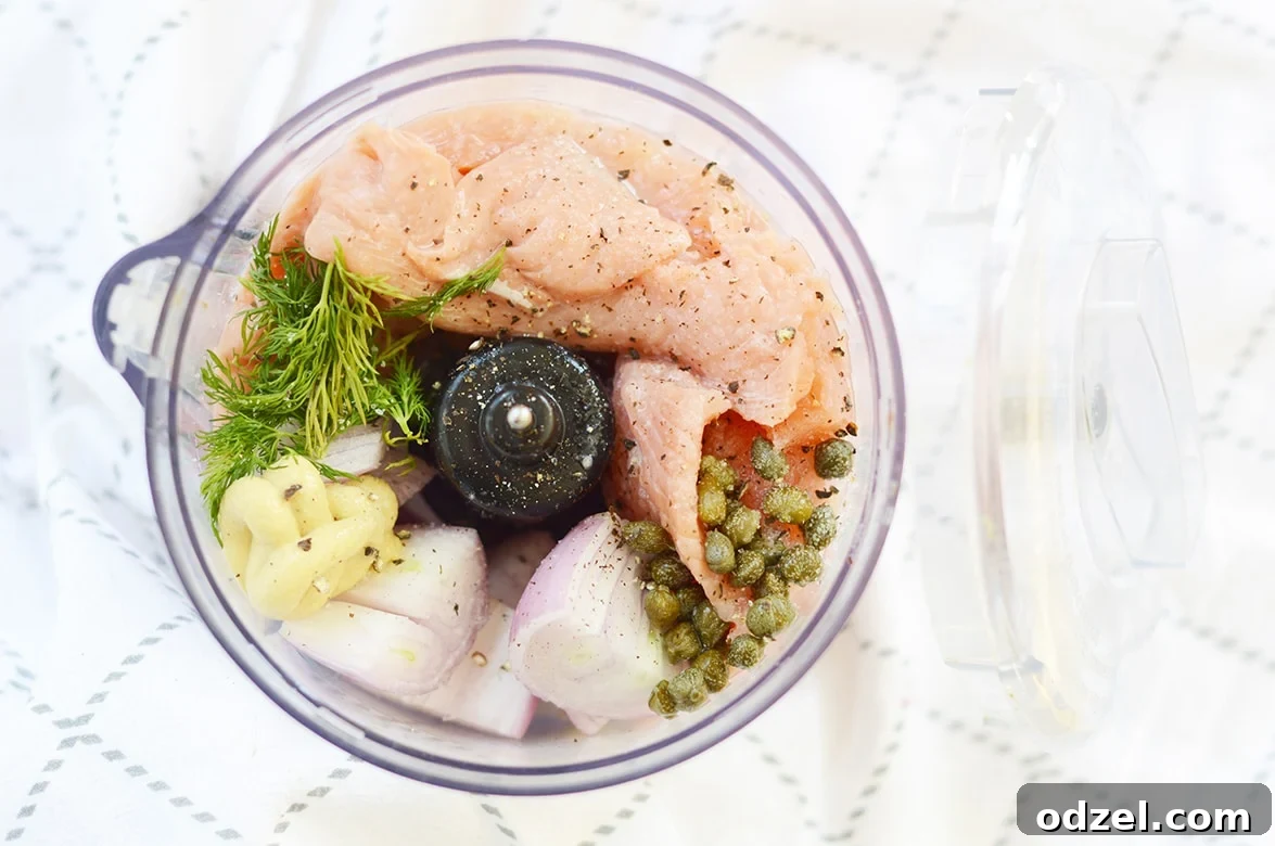 Zesty Salmon Burgers 3 Ingredients for salmon burgers in a food processor, ready to be blended.