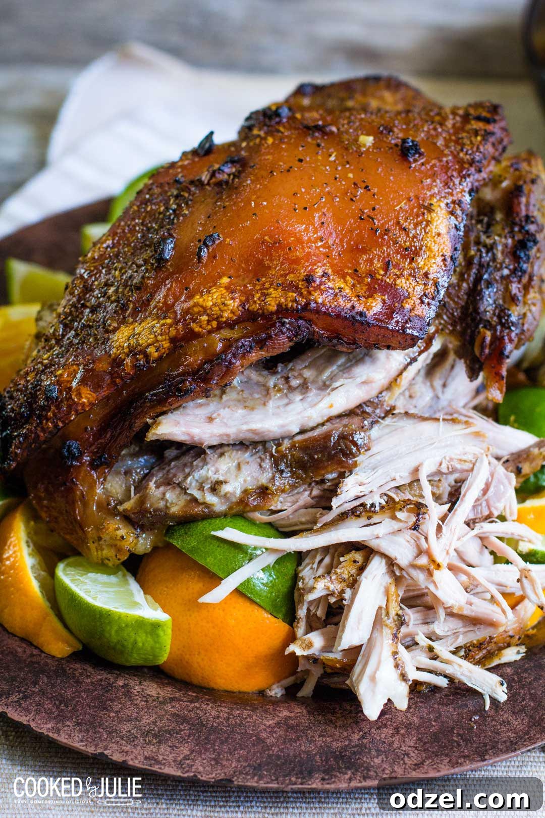 Perfectly roasted Cuban Pernil, a juicy pork shoulder with golden crispy skin, served with fresh orange and lime slices for garnish.
