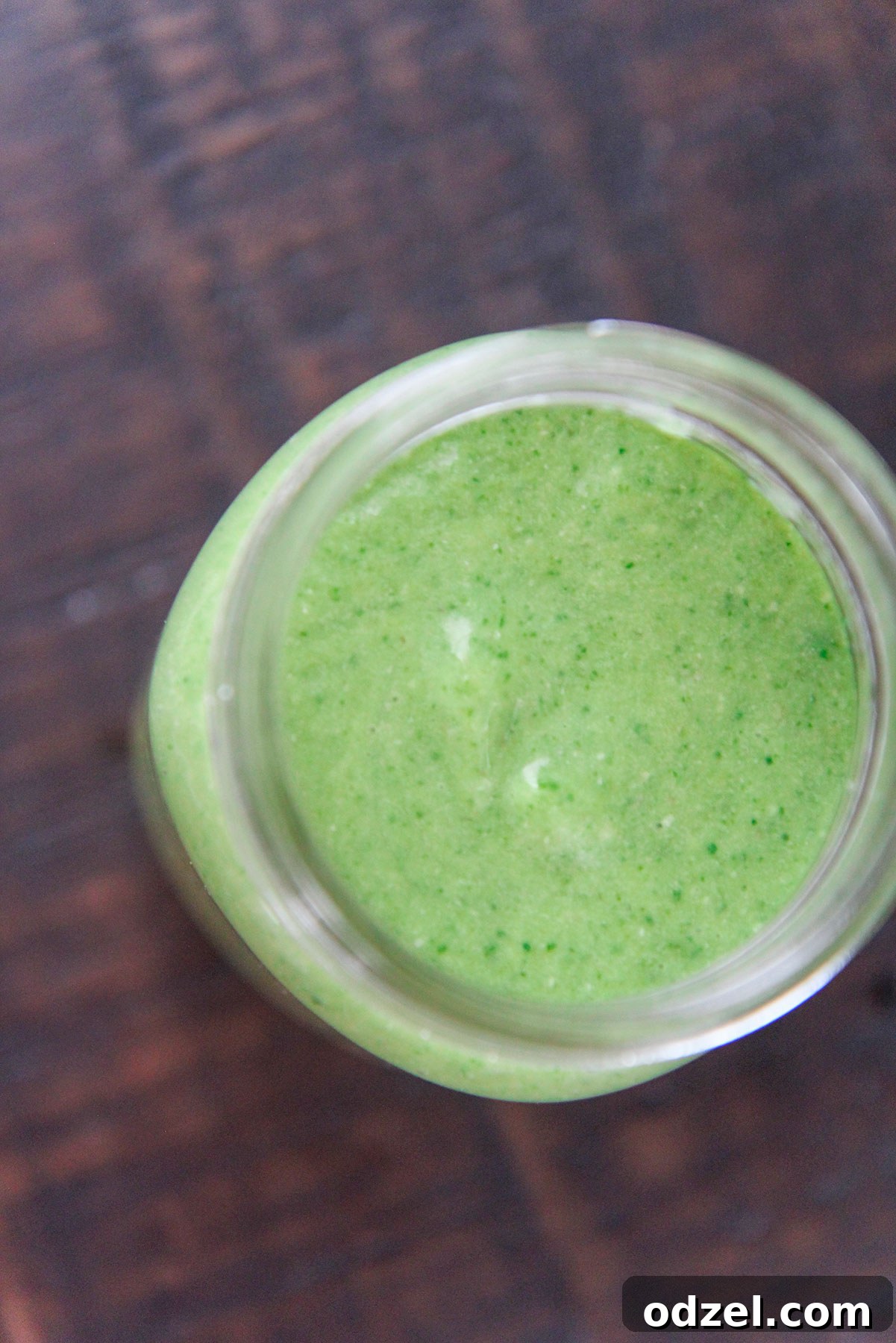 A refreshing green smoothie in a mason jar, perfectly blended and ready to be enjoyed on a rustic wooden table.