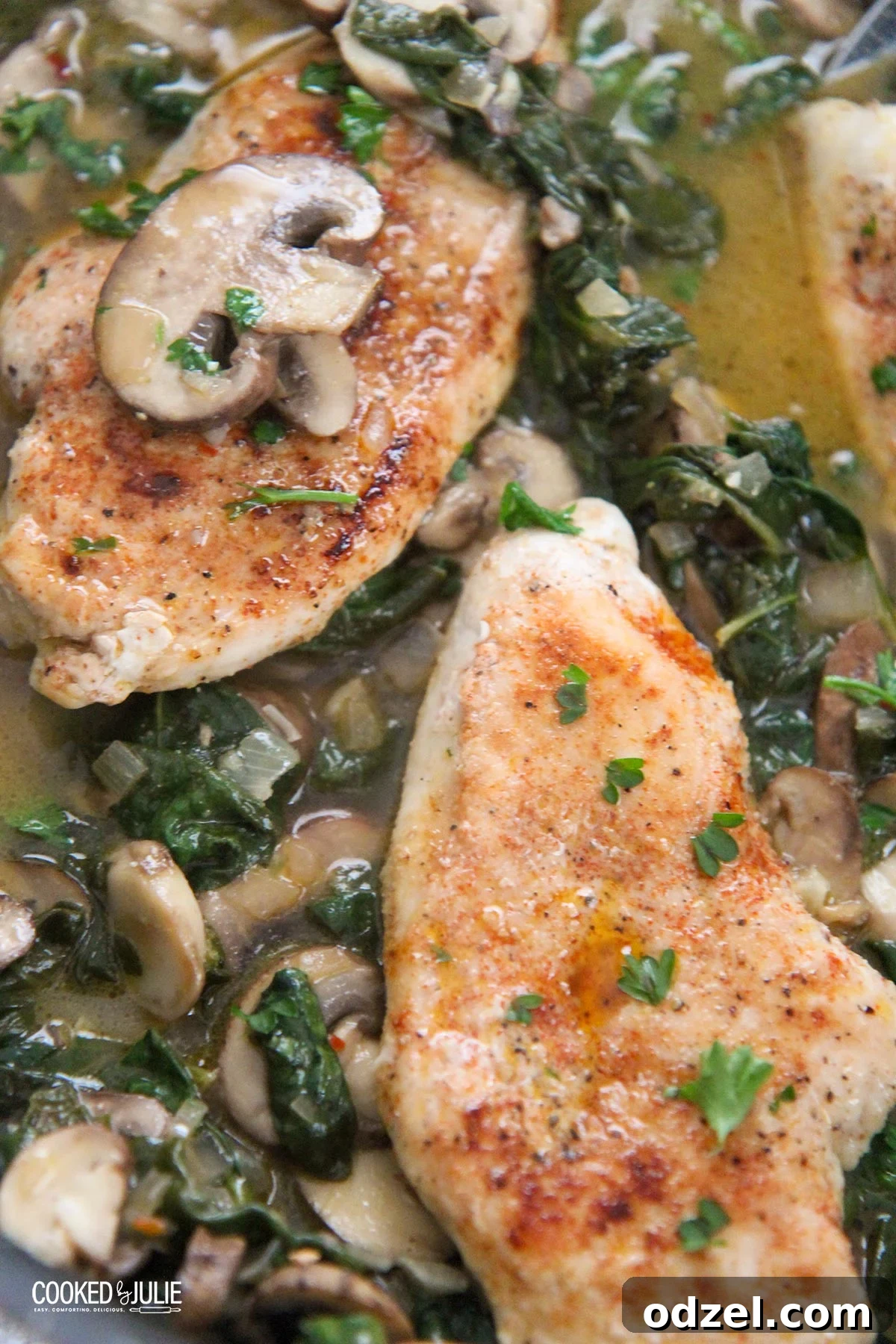 Chicken, spinach, and mushrooms sizzling in a hot skillet, garnished with fresh herbs.