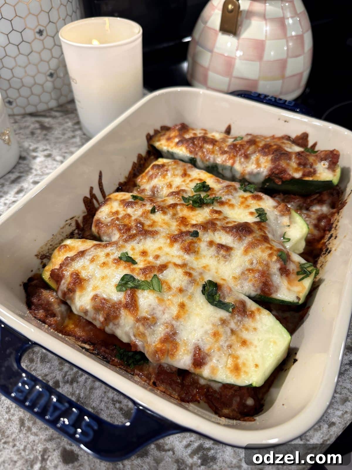 Lasagna stuffed zucchini boats with rich meat sauce and melted mozzarella cheese, garnished with fresh herbs.