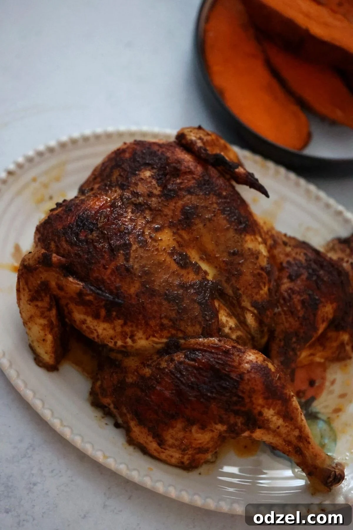 Close-up of a perfectly cooked spatchcock chicken, golden-brown and juicy, resting on a cutting board.