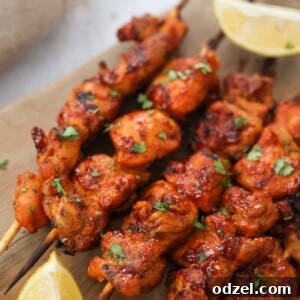 Pinchos de pollo on a wooden board with lemon wedges on the side.
