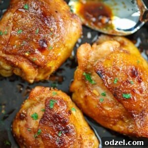 Three honey garlic chicken thighs in a skillet with a spoon.