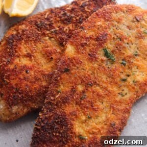 Two crispy chicken cutlets with a lemon wedge on the side.