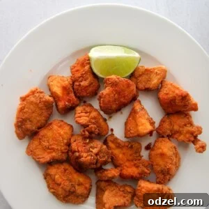 Chicharron de Pollo, crispy chicken bites, on a white plate with a lime wedge.