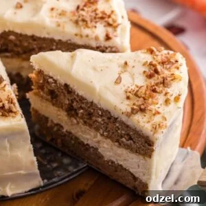 Layered carrot cake cheesecake with cream cheese frosting and chopped pecans on a wooden cake stand.