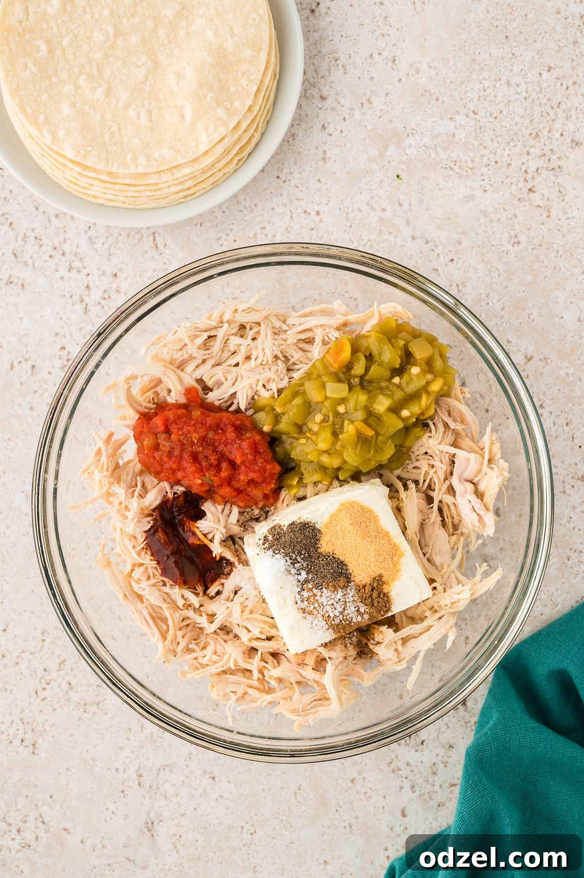 Smoky Chipotle Chicken Flautas 4 shredded chicken and other ingredients in a glass bowl with tortillas on the side.