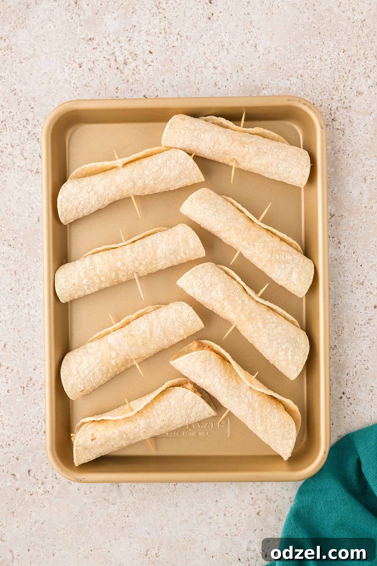 Smoky Chipotle Chicken Flautas 6 rolled tortillas with toothpicks on a baking sheet.