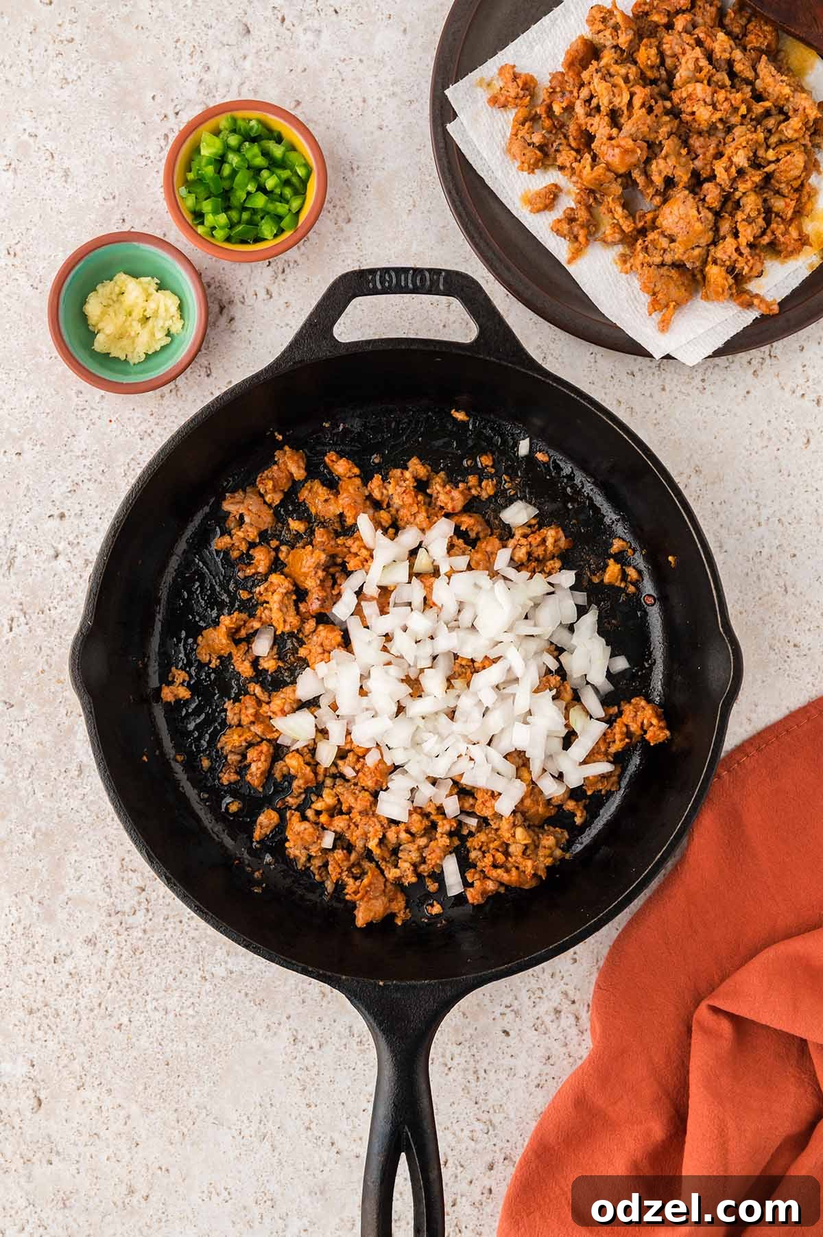 Melted Queso con Chorizo Dip Recipe for Parties 4 chorizo and onions in a black iron skillet.