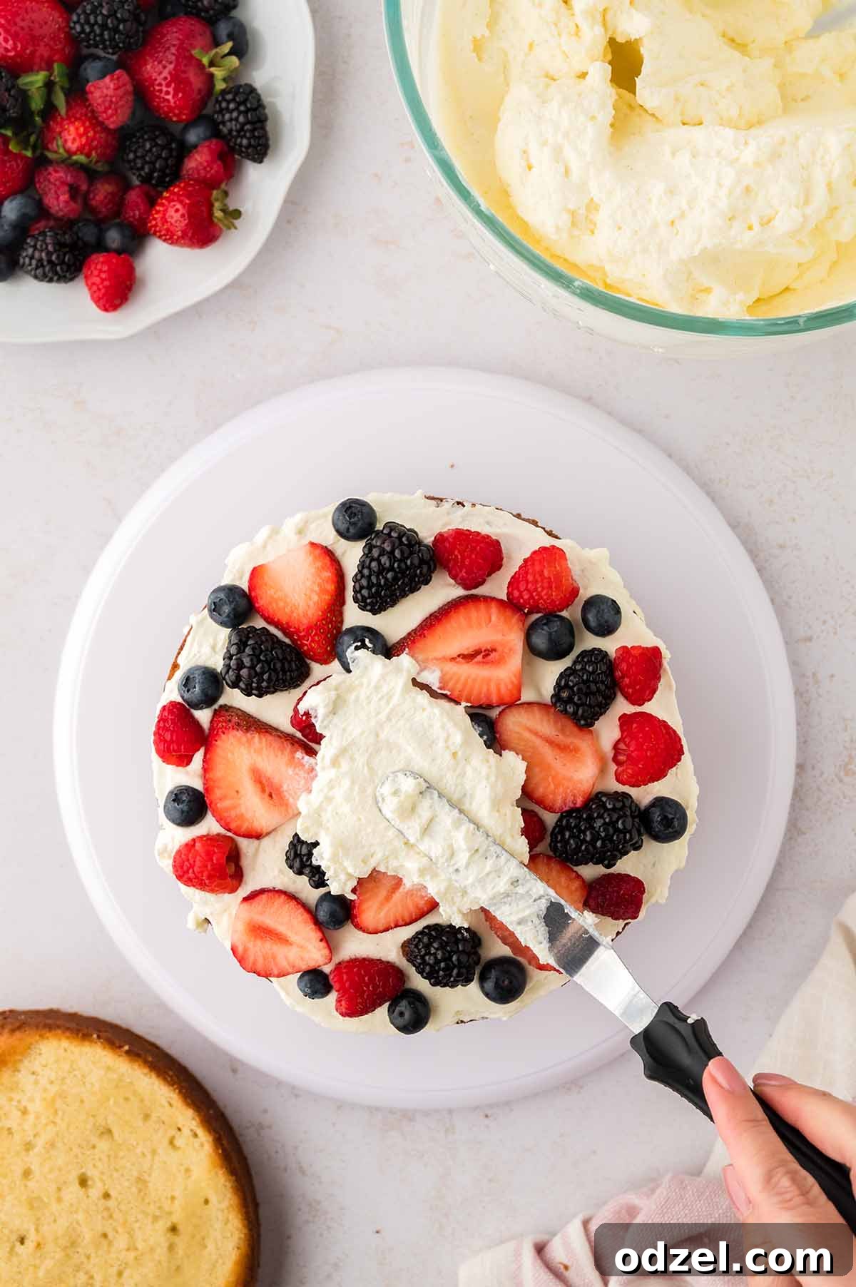 Light and Creamy Chantilly Cake Recipe for Special Occasions 7 Cake layer being decorated with fruit and frosting.