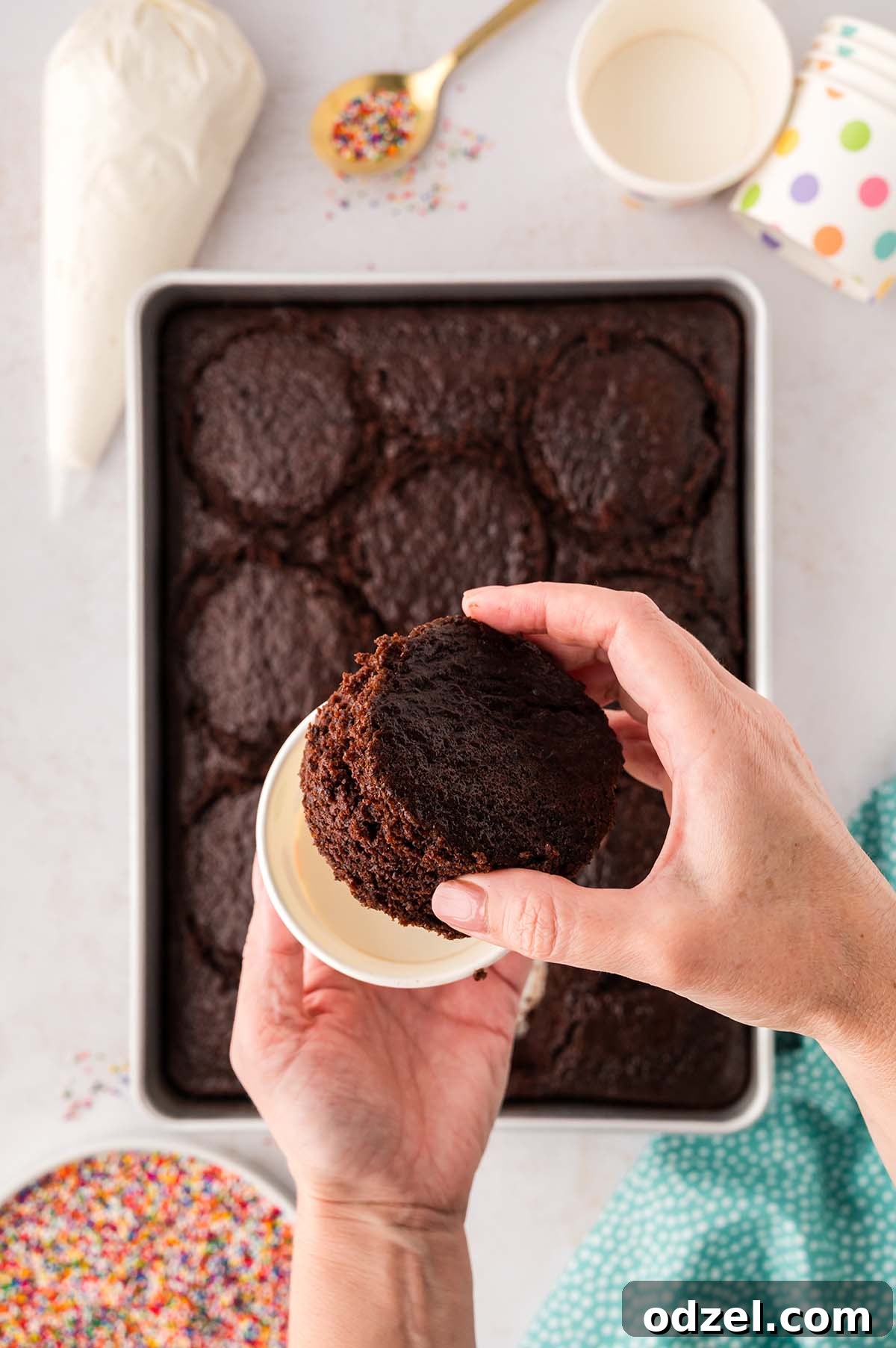 Copycat Dot Cakes Recipe: Make Classic Mini Cake Bites at Home 7 Hand placing a chocolate cake round into a paper cup.