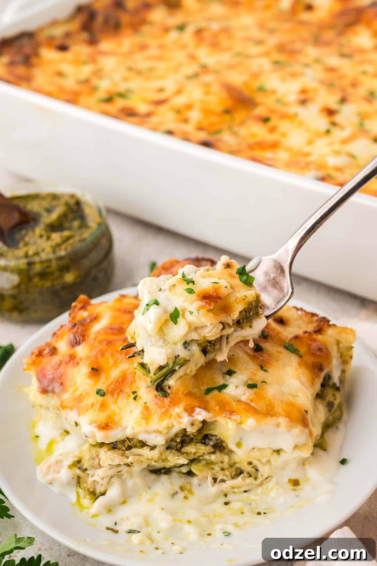 Creamy Pesto Chicken Lasagna Recipe 3 A slice of lasagna with a fork.