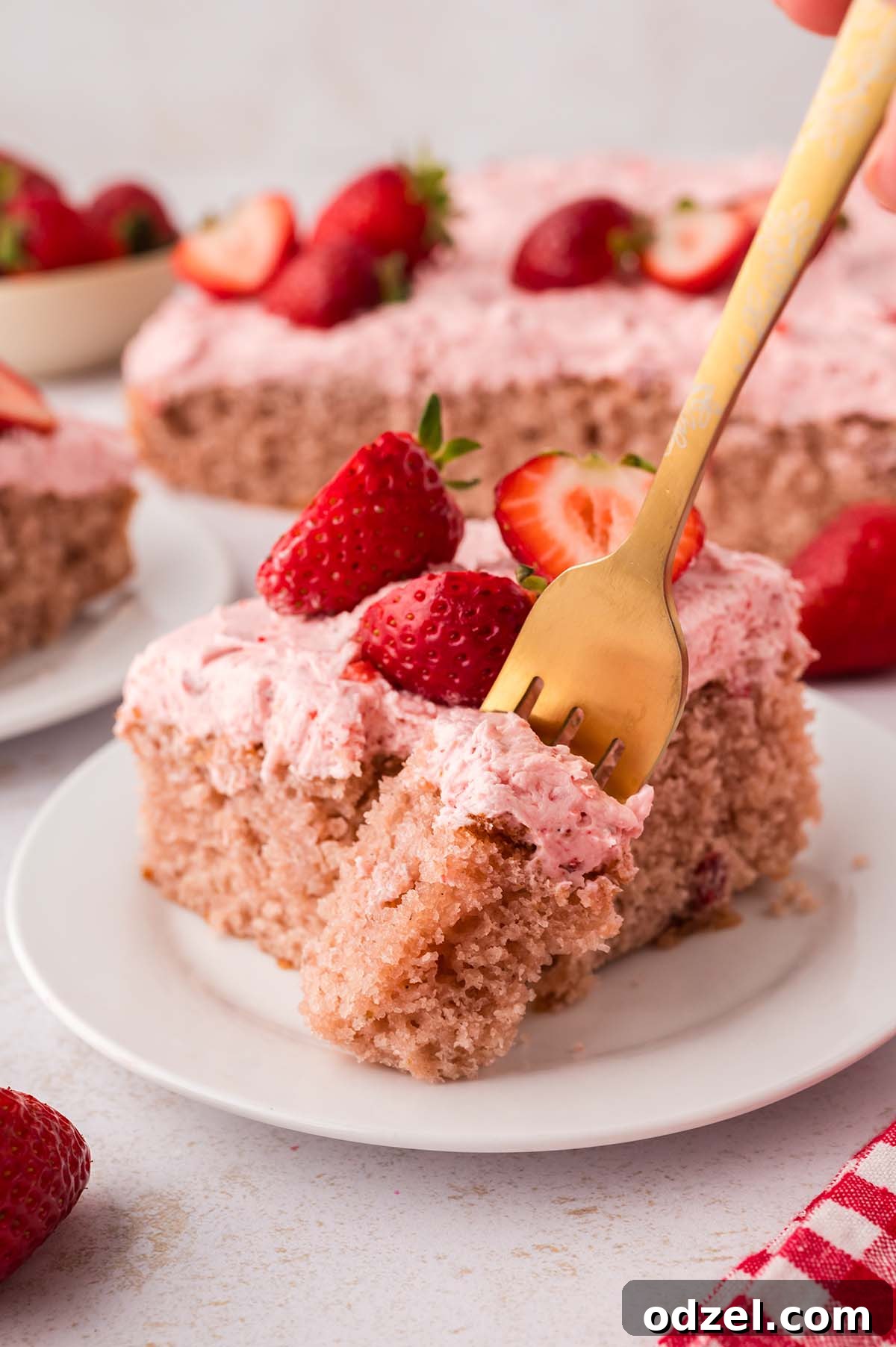 Moist Fresh Strawberry Sheet Cake Recipe 9 A gold fork cutting into a slice of cake.