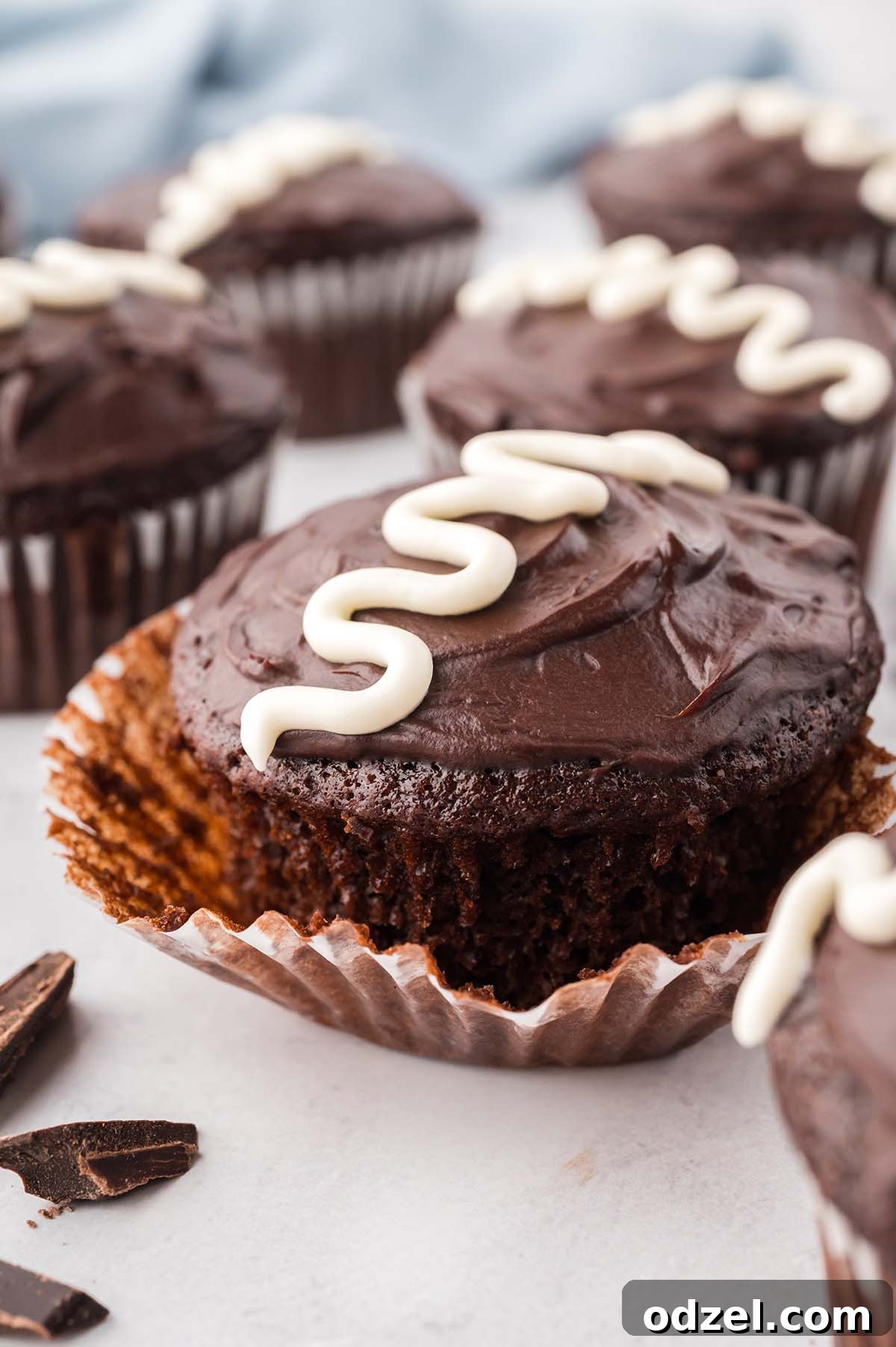 Gooey Marshmallow-Filled Chocolate Cupcakes 8 a chocolate cupcake with chocolate ganache and a white swirly line on top.