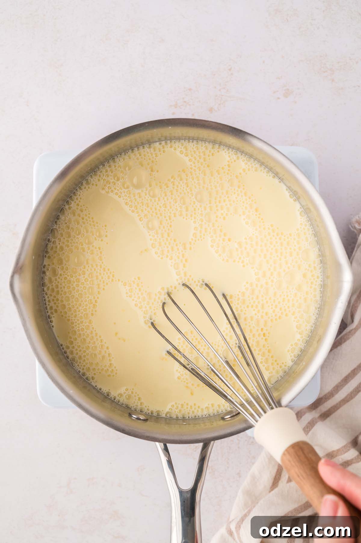 Southern Classic Banana Pudding Recipe 5 yellow thin liquid in a saucepan with a whisk.