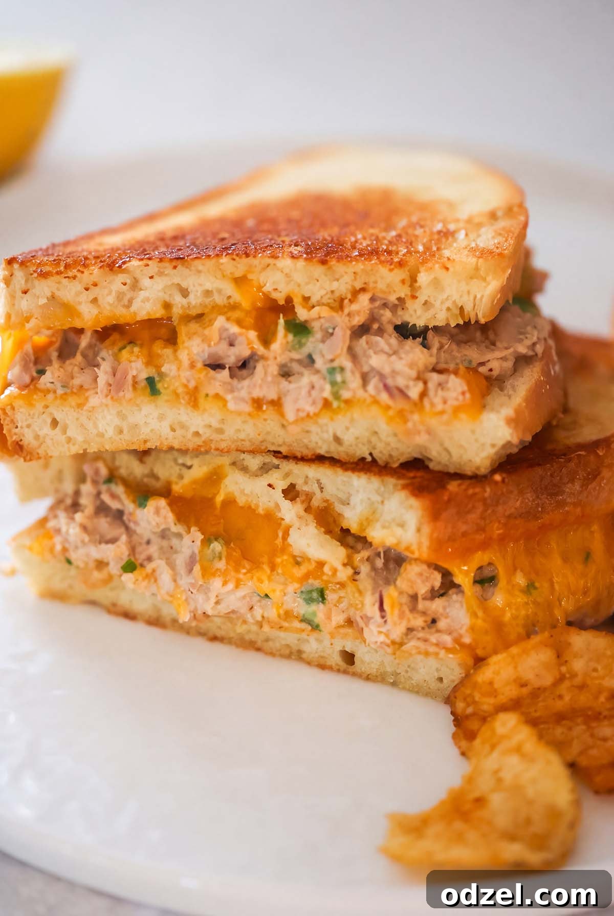 Crispy Spicy Tuna Melt with Sriracha Aioli 6 Two spicy tuna melt sandwiches stacked on top of each other and chips on the side.