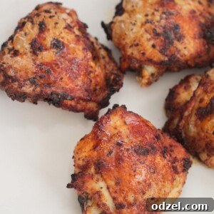 four air fryer chicken thighs on a white plate.