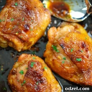 Three honey garlic chicken thighs in a skillet with a spoon.