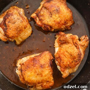 four pan-seared chicken thighs in a cast iron skillet.