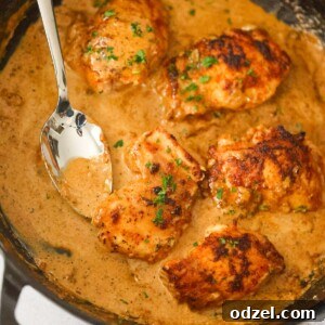 creamy spicy chicken thighs in a skillet with a spoon.