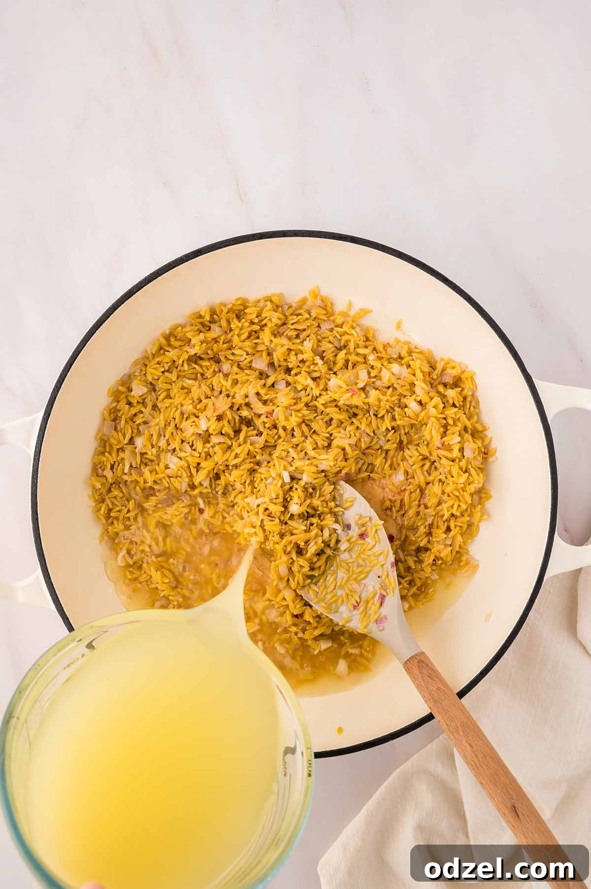 Creamy Lemon Garlic Lobster Orzo Recipe 6 chicken stock being poured into a skillet with orzo.