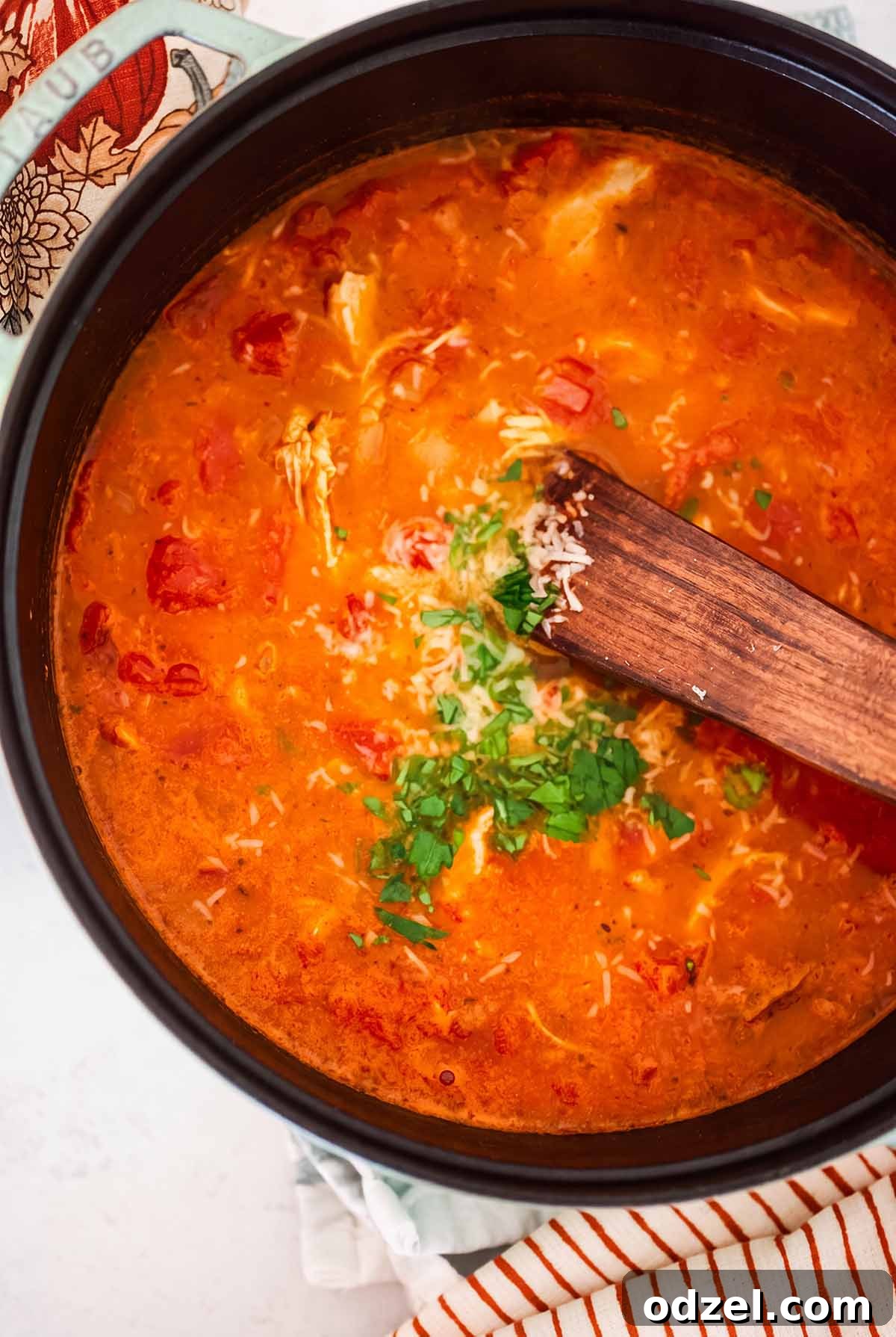 Comforting Chicken, Tomato and Lentil Soup Recipe 5 a pot filled with soup and a wooden spoon.
