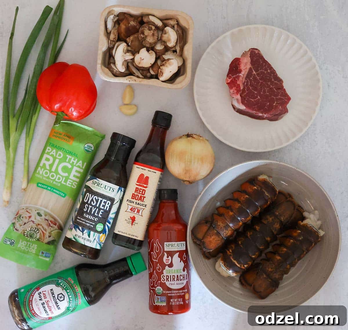 raw steak, lobster tails, red pepper, garlic, onions, mushrooms, rice noodles, and sauces.