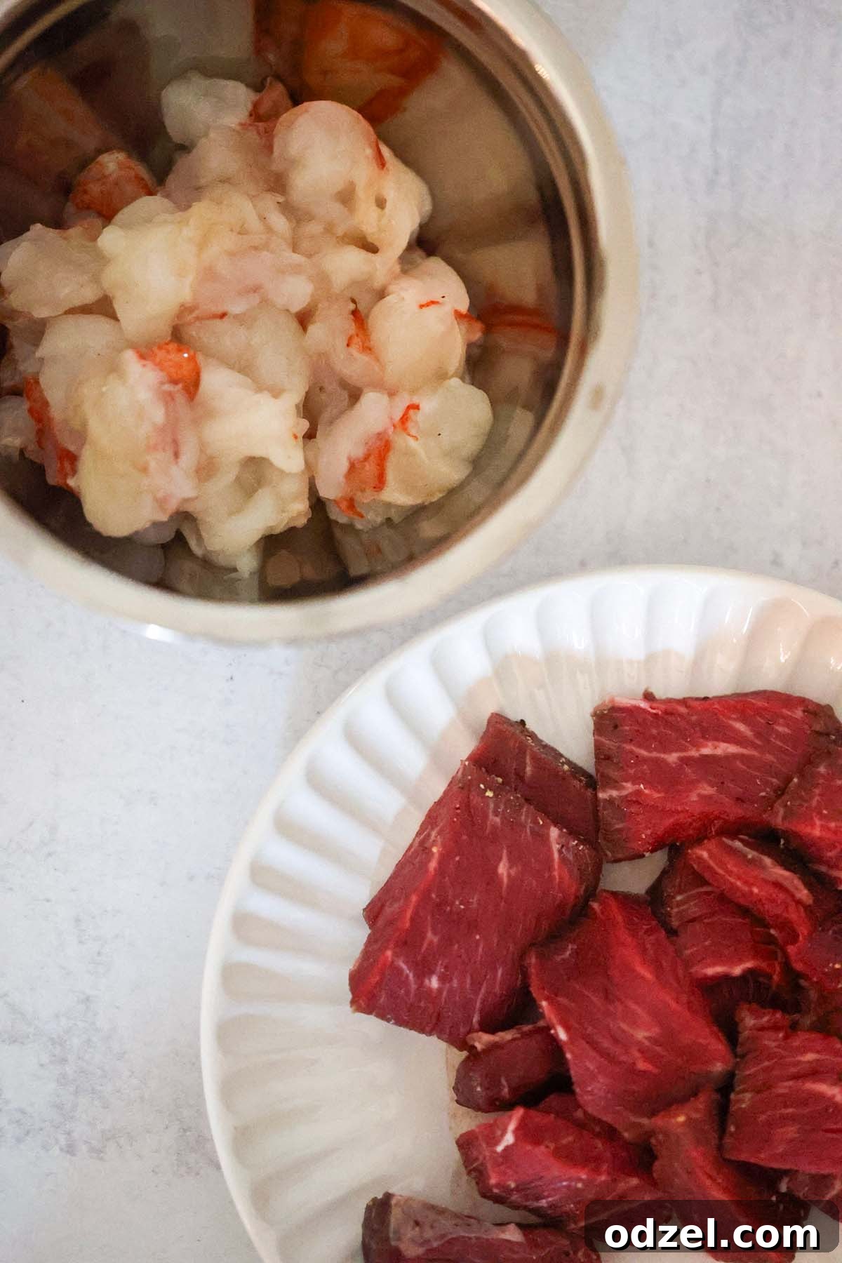 raw lobster meat in a bowl and raw steak on a plate.