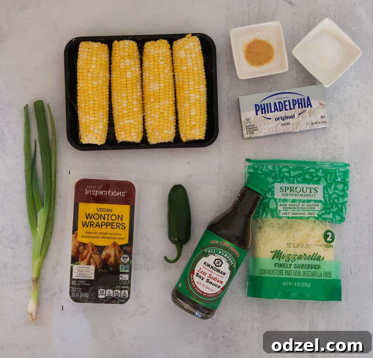 Crispy Sweet Corn and Cheese Rangoons 3 corn, cheese, garlic, cheese, jalapeño pepper, soy sauce, wonton wrappers, and scallions on a gray surface.